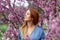 Beautiful dreaming redhead woman in spring time blossom cherrytrees garden