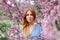 Beautiful dreaming redhead woman in spring time blossom cherrytrees garden