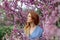 Beautiful dreaming redhead woman in spring time blossom cherrytrees garden