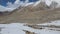 Beautiful drone footage of the mountain ranges covered in snow with a herd of yak grazing in the fields