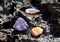 A beautiful druse and geode of amethyst and druse of citrine lie on a stone. Crystals of semi-precious stones in the sun