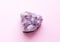 Beautiful druse of natural purple mineral amethyst on a pink background. Large crystals of a gem