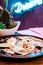 Beautiful dumplings with sour cream on a black plate on the background of a neon sign in a restaurant