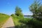 Beautiful dutch rural landscape with riverside cycle path, agricultural field, river Maas, blue sky - Maasheggen biosphere reserve