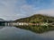 Beautiful early morning panoramic view of a creek with reflections of blue sky, boats, foggy mountains and trees on water