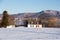 Beautiful early morning winter view of patrimonial white wooden house with steep shingled roof and shed in rural setting