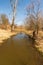 Beautiful early springtime scenery with creek, trees and clear sky