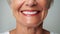 Beautiful elder womans smile with healthy white, straight teeth close-up on light background with space for text