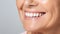 Beautiful elder womans smile with healthy white, straight teeth close-up on light background with space for text