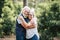 Beautiful elderly lifestyle senior couple hug and stay in love touching during outdoor leisure activity in the wood forest - green