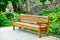 A beautiful and elegant oak bench stands in a park in a recreation area on paving slabs