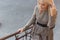 Beautiful elegant slim blonde girl in elegant dress with brooch up the stairs in the city