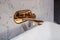 Beautiful elegant soft shaped square sink with golden water tap and marble wall. Close up photo with selective focus