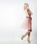 Beautiful elegant striking blonde woman with bright makeup in pink dress with dlinnymi slender legs in Studio on white