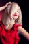 Beautiful elegant striking blonde woman with bright makeup red lips in a red dress in the Studio on a black background