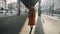 Beautiful elegant tourist woman walks along Paris street under metro flyover, looking back at camera smiling slow motion