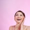 Beautiful elegant woman with bare shoulders clean skin spa treatments isolated on pink background