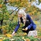 Beautiful elegant woman collects leaves in a park in autumn