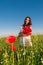 Beautiful elegant woman over Sky and Sunset in the field holding a poppies bouquet, smiling.