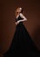 Beautiful elegant young model with bright redhead hairstyle posing in fashion chic black wedding dress with long skirt on studio