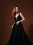 Beautiful elegant young model with bright redhead hairstyle posing in fashion expensive black wedding dress with long skirt on