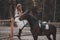 Beautiful and elegant young woman wearing the dress is stroking the horse on the ranch