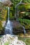 Beautiful emerald color waterfall flowing over stones covered in moss