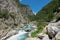 Beautiful emerald river rushes along the empty asphalt road in the French Alps.