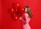 Beautiful emotional girl in pink dress with red ballons on red background