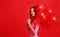 Beautiful emotional girl in pink dress with red ballons on red background