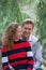 Beautiful enamored young couple sitting on a tree trunk in the forest. Facial expression is in love