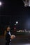 Beautiful Energetic Fitness Female in Fenced Outdoor Basketball Court. At Night