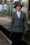 Beautiful english woman dressed in 1920s costume walking on railway platform with train in background