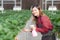 Beautiful entrepreneur young asian woman standing and watering strawberry plants in farm at greenhouse.