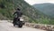 Beautiful epic shot of young determined and empowered man driving black vintage motorcycle. Footage. Down empty mountain