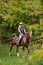 Beautiful equestrian country girl riding horse in the autumn forest