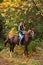 Beautiful equestrian country girl riding horse in the autumn forest