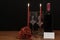 Beautiful etched wine glasses and bottle of red wine, red candles and red roses on wooden table with name tag on dark background