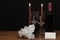 Beautiful etched wine glasses and bottle of red wine, red candles and white roses on wooden table with name tag on dark background