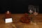 Beautiful etched wine glasses with red roses and red candle on wooden table and dark background