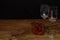 Beautiful etched wine glasses with a single red rose on wooden table and dark background