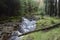 Beautiful ethereal style landscape image of small brook flwoing through pine trees in Peak District in England