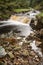 Beautiful ethereal style landscape image of small brook flwoing through pine trees in Peak District in England