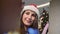 Beautiful European woman wearing Santa Claus hat opening gift box and smiling looking inside