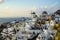 Beautiful evening light scene of Oia white building townscape and windmill along island mountain, vast ocean, soft cloud