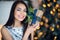 Beautiful excited smiling young woman with present gift feeling happy near christmas tree. Close-up portrait