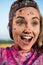 Beautiful excited woman with colorful paint on face and clothes looking away at holi festival