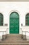 Beautiful exterior of a traditional green wooden door with stairs and green arch metal windows