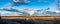 Beautiful extra wide and large slow tornado panorama over scandinavian forest and field, sunny day with very heavy dark clouds ,