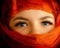 Beautiful eyes of a girl close-up. The head and lips are covered with an orange cloth, a veil. The girl in the headscarf.